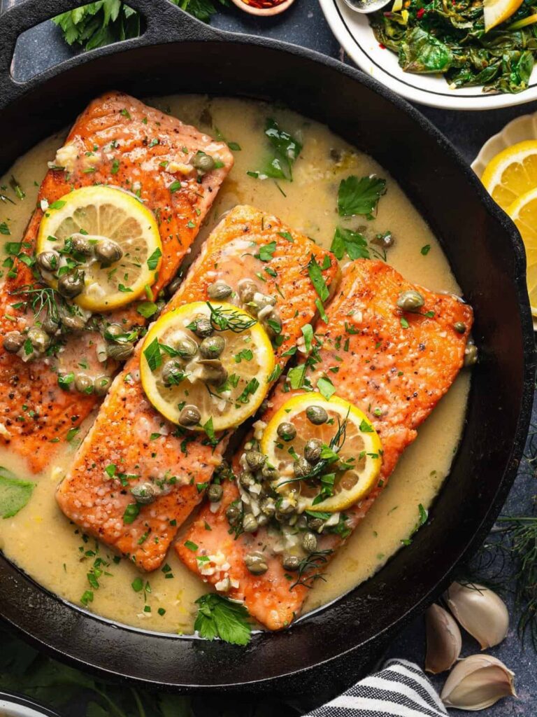 Seared salmon fillets with lemon and capers in a black cast iron skillet