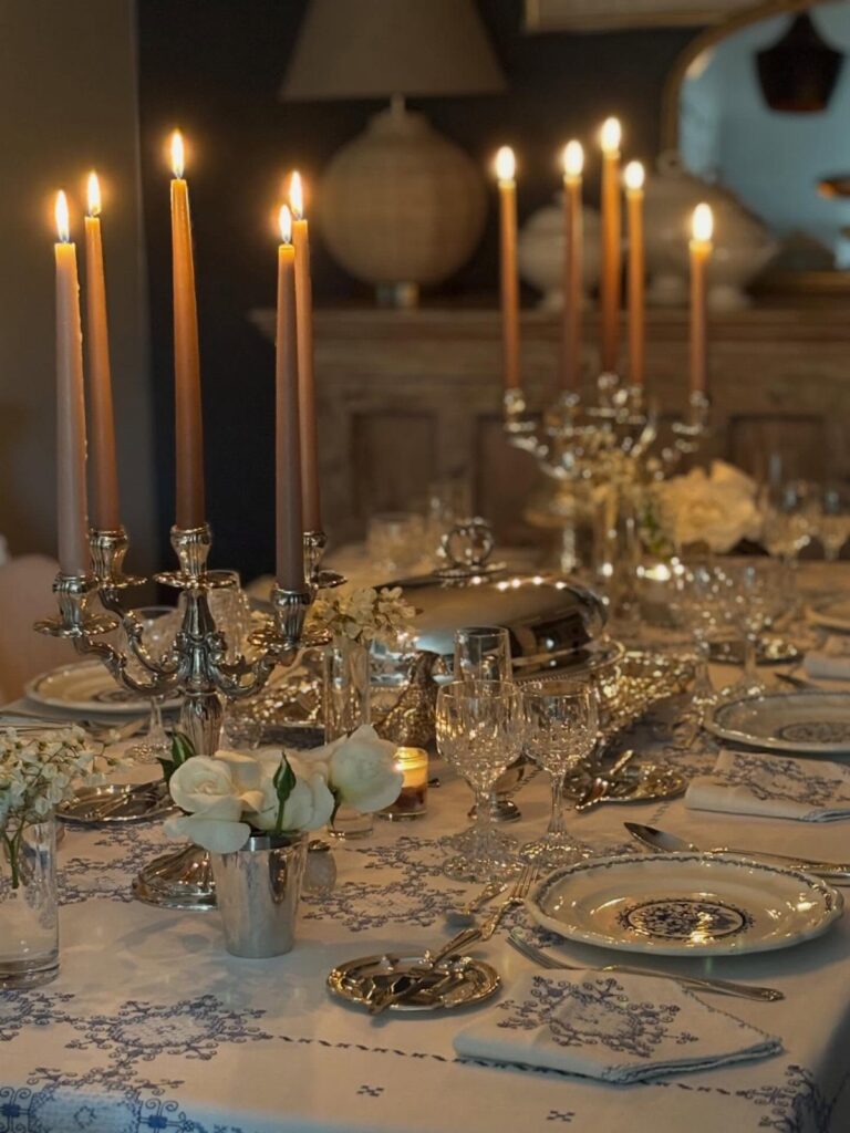 Silver candelabras with lit candles and white roses on a formal dinner table.