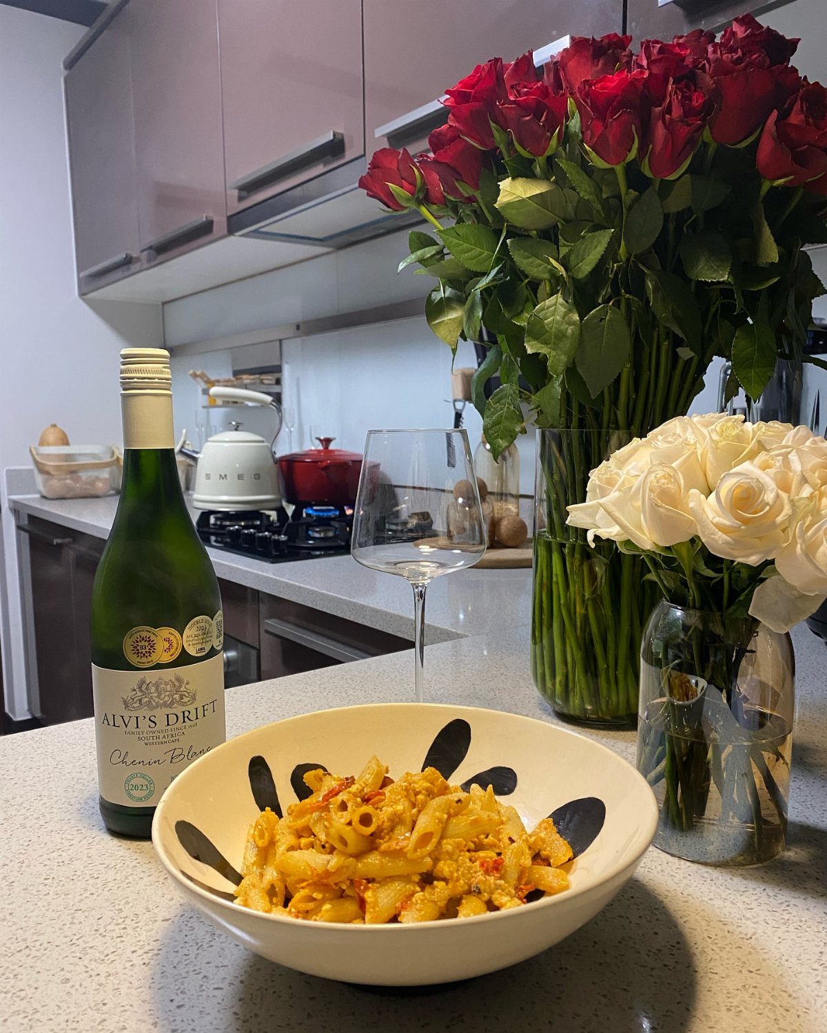 Creamy feta pasta in a bowl with white wine and fresh roses.