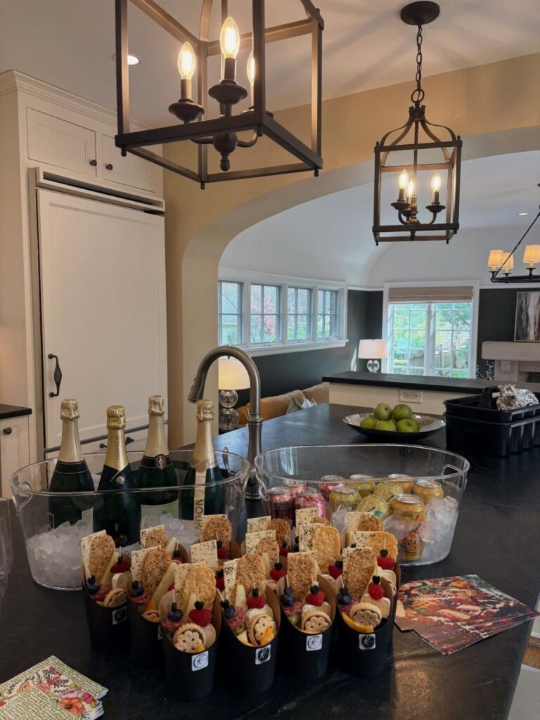 Appetizer cups and champagne bottles arranged on a dark kitchen island for guests.