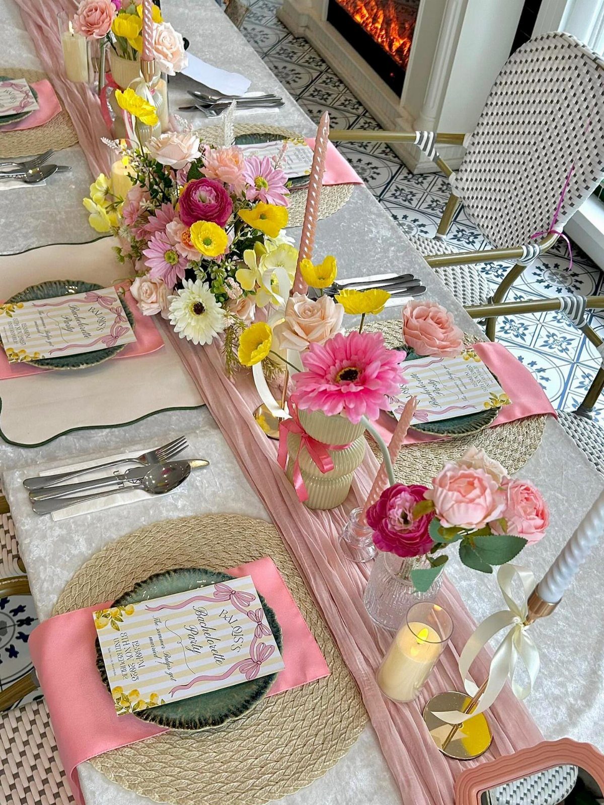 Decorated party table with pink runner, colorful flower arrangements, and elegant place settings.