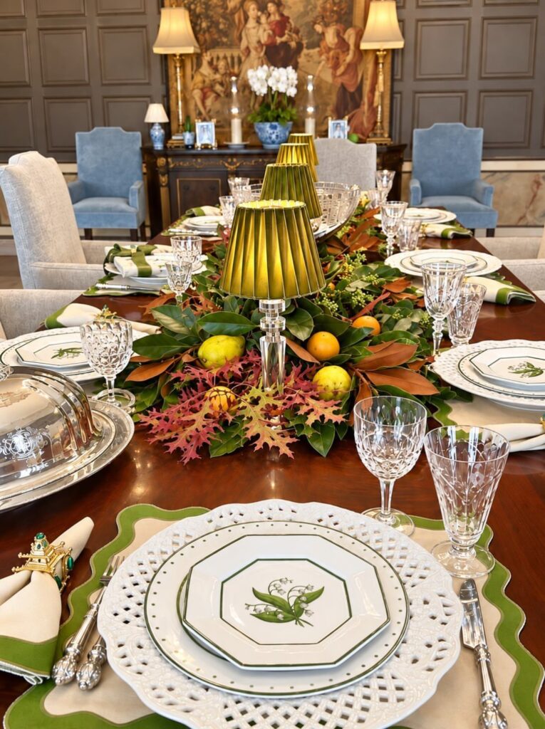 Formal dining table arrangement with autumn foliage, yellow lemons, and small lamps.