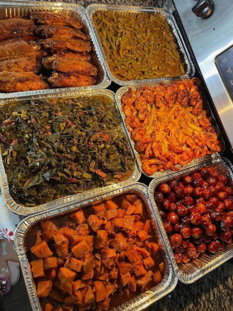 Assorted Thanksgiving side dishes and chicken wings in aluminum foil catering trays.