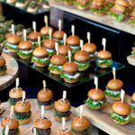 Mini sliders with beef and lettuce on wooden platters for a reception.