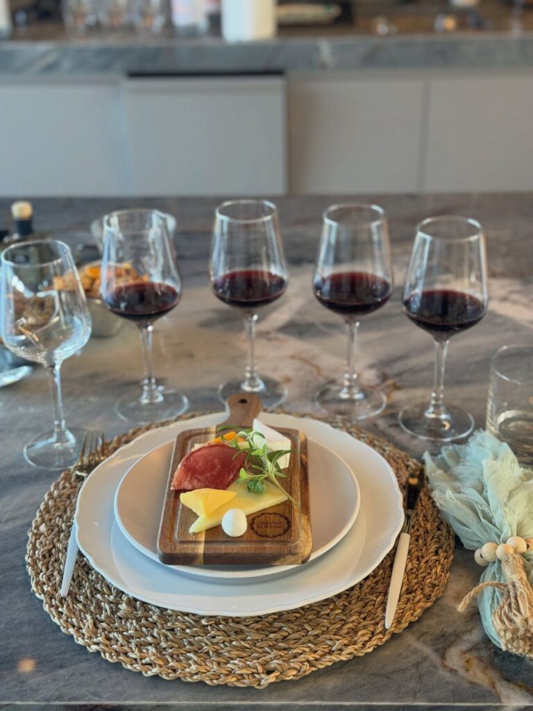 Red wine glasses and a charcuterie board arranged on a marble kitchen counter.